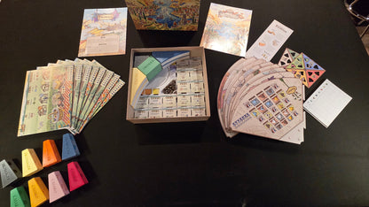 Board game components including cards and pieces on a dark surface