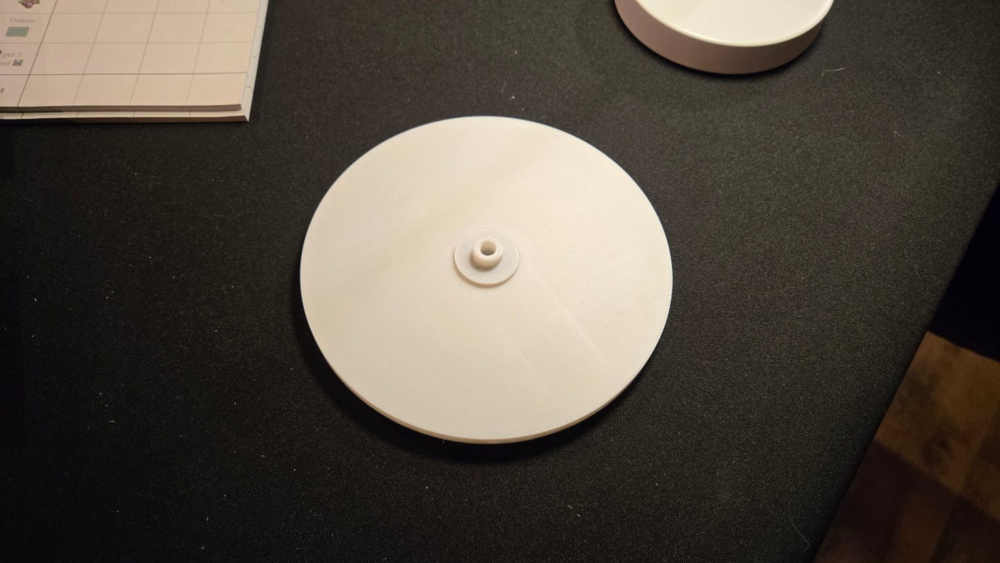 Round white object on a dark surface with a book in the background