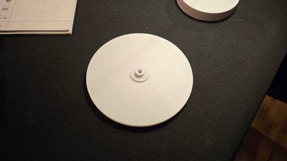 Round white object on a dark surface with a book in the background