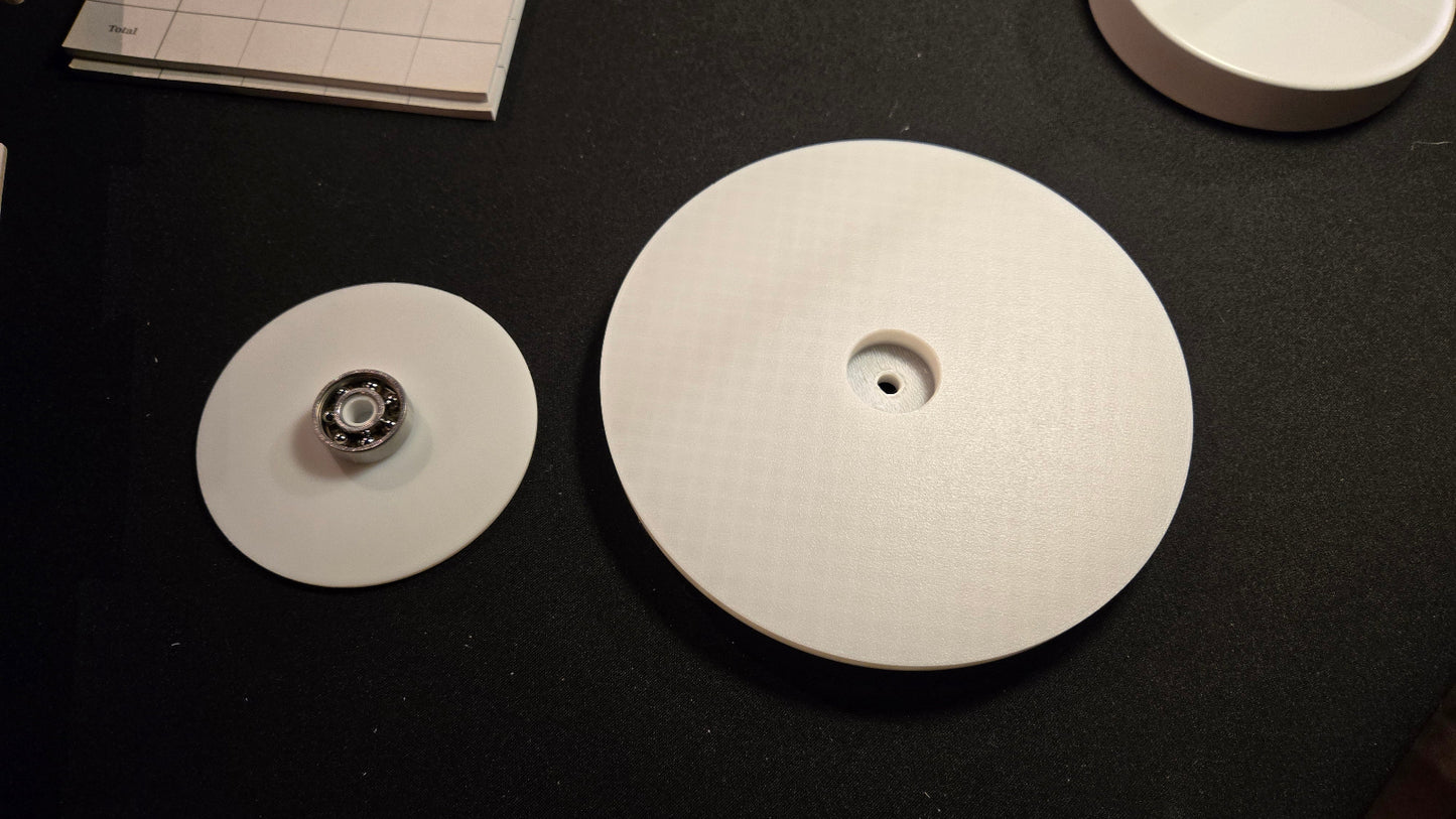 Three circular white objects on a black surface with a piece of paper in the background.