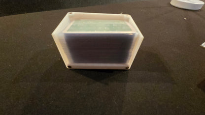 Hexagonal plastic container with a white lid on a dark surface