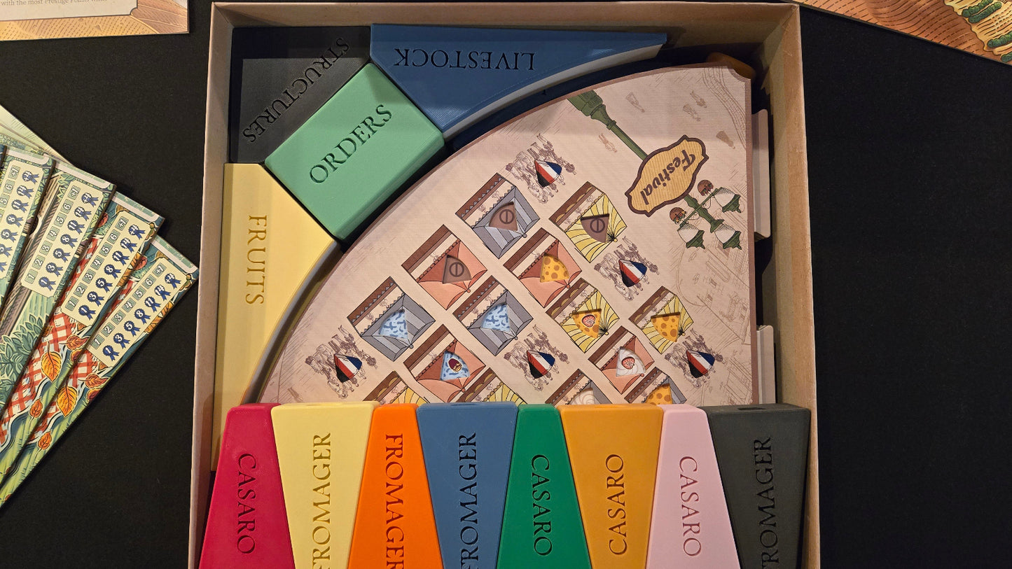 Board game components including cards and a board in a box on a dark surface