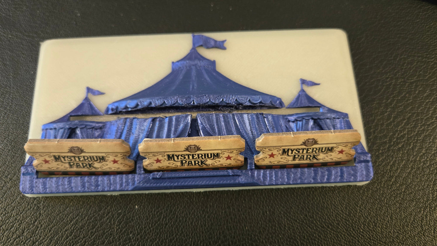 Decorative item with a blue tent and 'Mysterium Park' signs on a dark surface