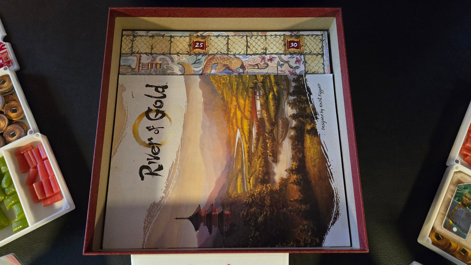 Board game box titled 'River of Gold' with scenic artwork on a dark background