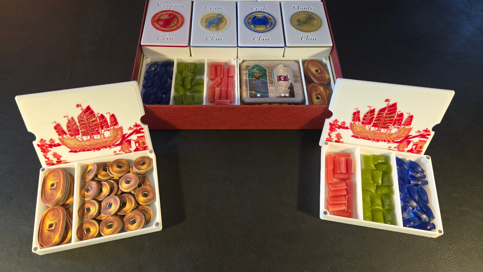 Colorful game pieces in a box with decorative lids on a dark surface