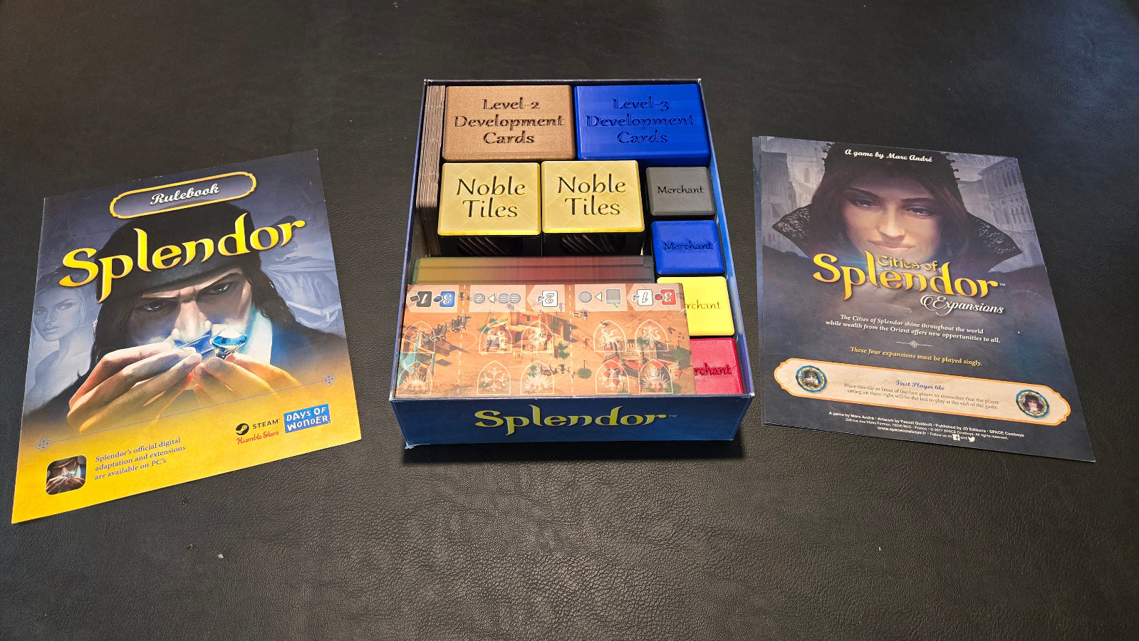 Board game 'Splendor' packaging including box, cards, and tiles on a dark surface