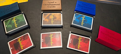 Collection of 'Splendor' game cards and boxes on a dark surface