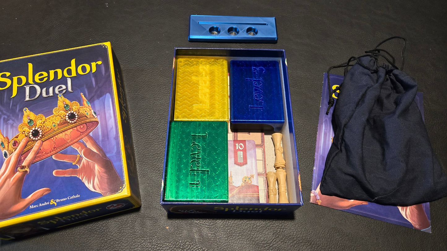 Board game components including 'Splendor Duel' box, color tiles, and a draw bag on a dark surface.