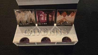 Cavekins product display with three cards and a stand on a dark background
