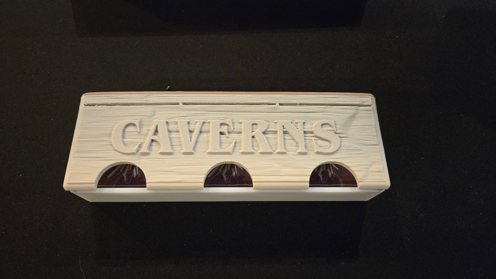 Wooden block with 'CAVERNS' engraved on a black background