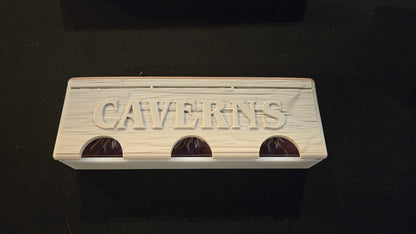 Wooden block with 'CAVERNS' engraved on a black background